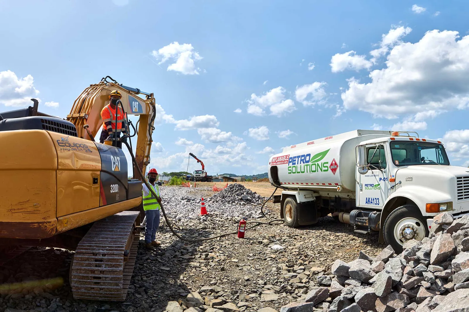 Camión cisterna de PetroSolutions abasteciendo de combustible a una excavadora en un terreno de roca y grava